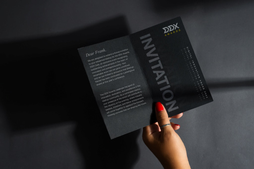 A hand holding a printed DDX invitation
